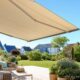 Terrasse mit großer heller Markise an einem sonnigen Sommertag